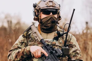 Soldado com uniforme camuflado e arma em posição de prontidão durante operação militar