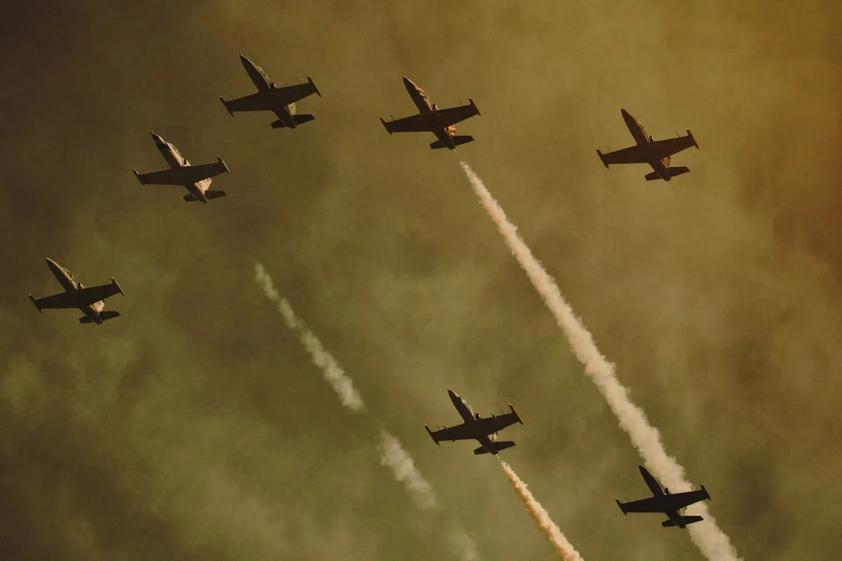 Aviões militares voando em formação com rastros de fumaça no céu durante operação aérea