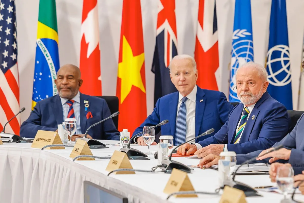Chefes de Estado sentados em reunião internacional com bandeiras de países ao fundo