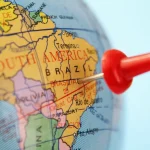 Mapa da América do Sul com foco no Brasil e marcador vermelho indicando o território brasileiro próximo a Brasília.