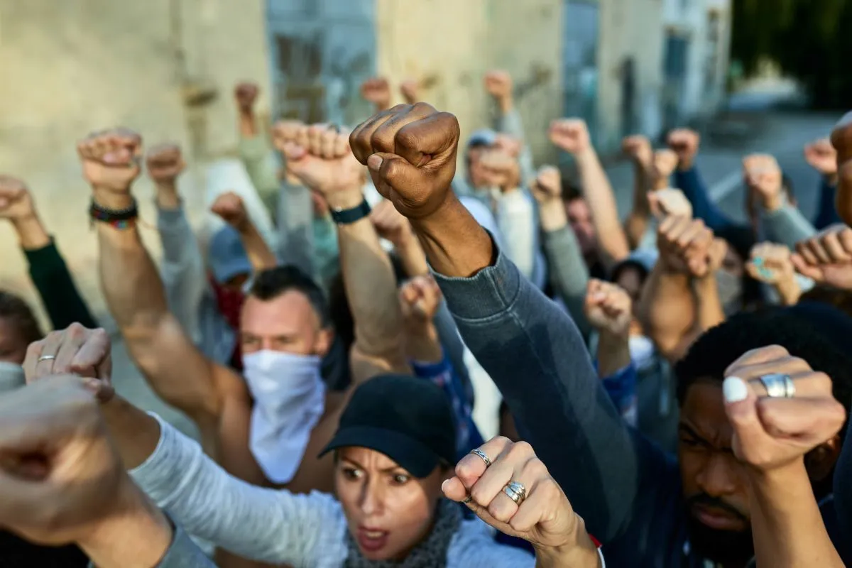 Grupo de manifestantes levantando punhos durante protesto de rua por direitos sociais e políticos