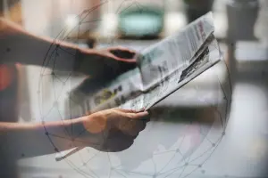 Pessoa segurando e lendo um jornal impresso com sobreposição de gráfico digital representando rede global de notícias e informação