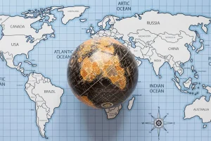 Globo terrestre sobre um mapa-múndi mostrando continentes como América, África, Europa, Ásia e oceanos ao redor