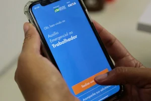 Pessoa utilizando aplicativo do Auxílio Emergencial no celular para consultar benefício social