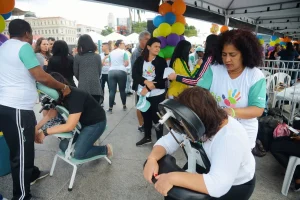 Profissionais realizando massagem em participantes durante ação social de saúde e bem-estar em evento público