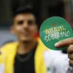 Pessoa segurando um adesivo verde com a frase “Brasil Soberano” em destaque