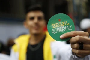 Pessoa segurando um adesivo verde com a frase “Brasil Soberano” em destaque