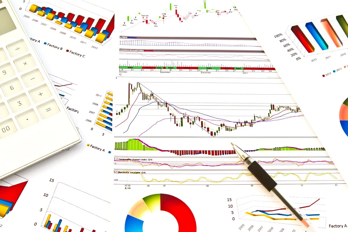 Gráficos financeiros impressos com calculadora e caneta representando análise de dados e investimentos