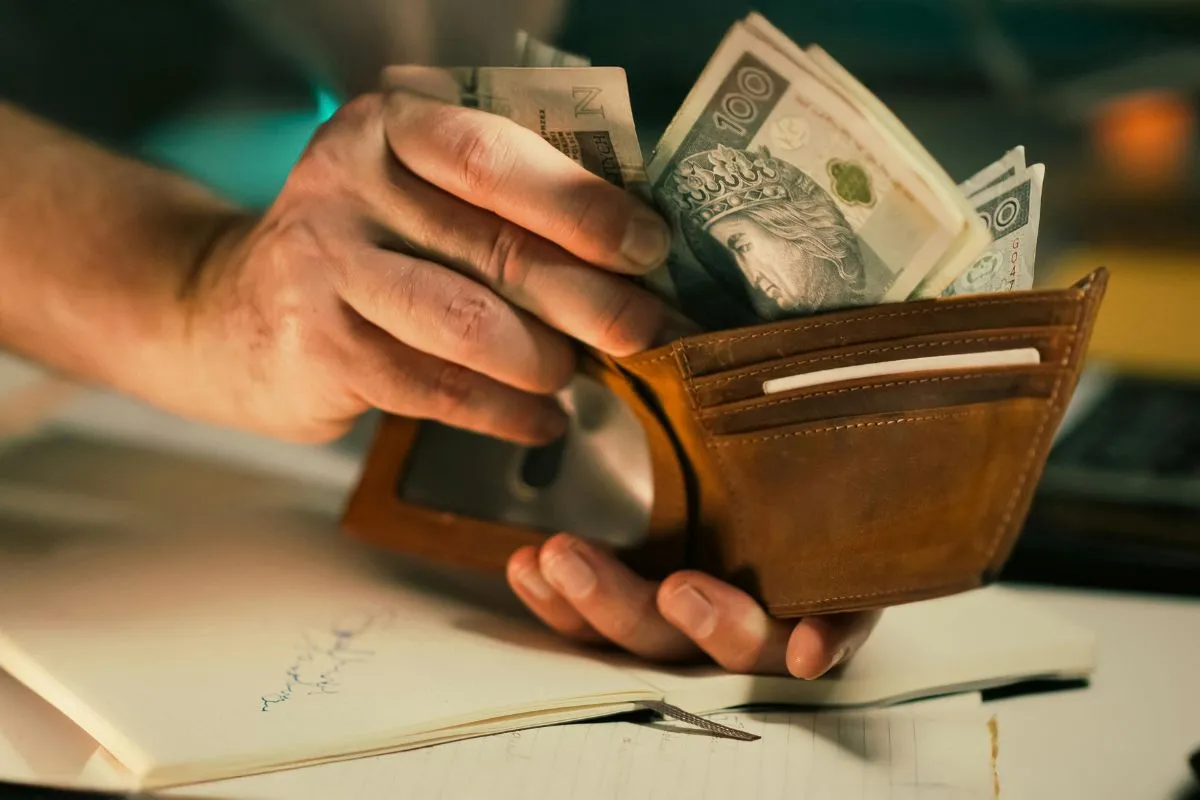 Pessoa segurando carteira com dinheiro em espécie representando controle financeiro e orçamento pessoal