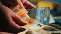 Pessoa contando notas de euro representando inflação e aumento do custo de vida na Europa