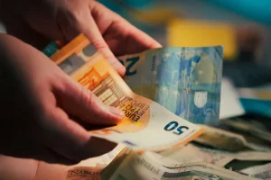 Pessoa contando notas de euro representando inflação e aumento do custo de vida na Europa