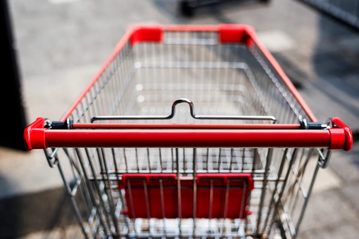 Carrinho de supermercado vazio em destaque simbolizando aumento de preços e crise econômica