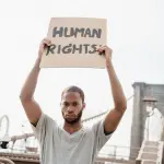 Homem segurando cartaz escrito “Human Rights” em manifestação por direitos humanos