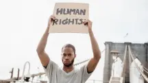 Homem segurando cartaz escrito “Human Rights” em manifestação por direitos humanos