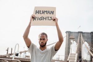 Homem segurando cartaz escrito “Human Rights” em manifestação por direitos humanos
