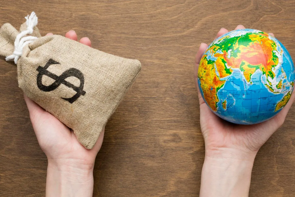 Mãos segurando globo terrestre e saco de dinheiro com símbolo de dólar representando economia global