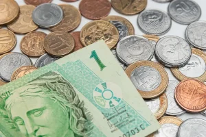 Cédula de um real sobre várias moedas brasileiras espalhadas representando economia e finanças no Brasil
