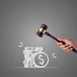 Mão segurando martelo de juiz prestes a atingir moedas empilhadas com símbolo de dólar, representando multa ou penalidade financeira