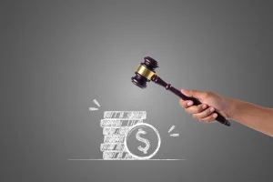 Mão segurando martelo de juiz prestes a atingir moedas empilhadas com símbolo de dólar, representando multa ou penalidade financeira