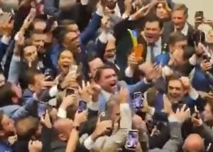 No centro da imagem, de terno claro, Flávio comemora resultado no Senado em meio a dezenas de aliados | Foto: Reprodução/X/@FlavioBolsonaro