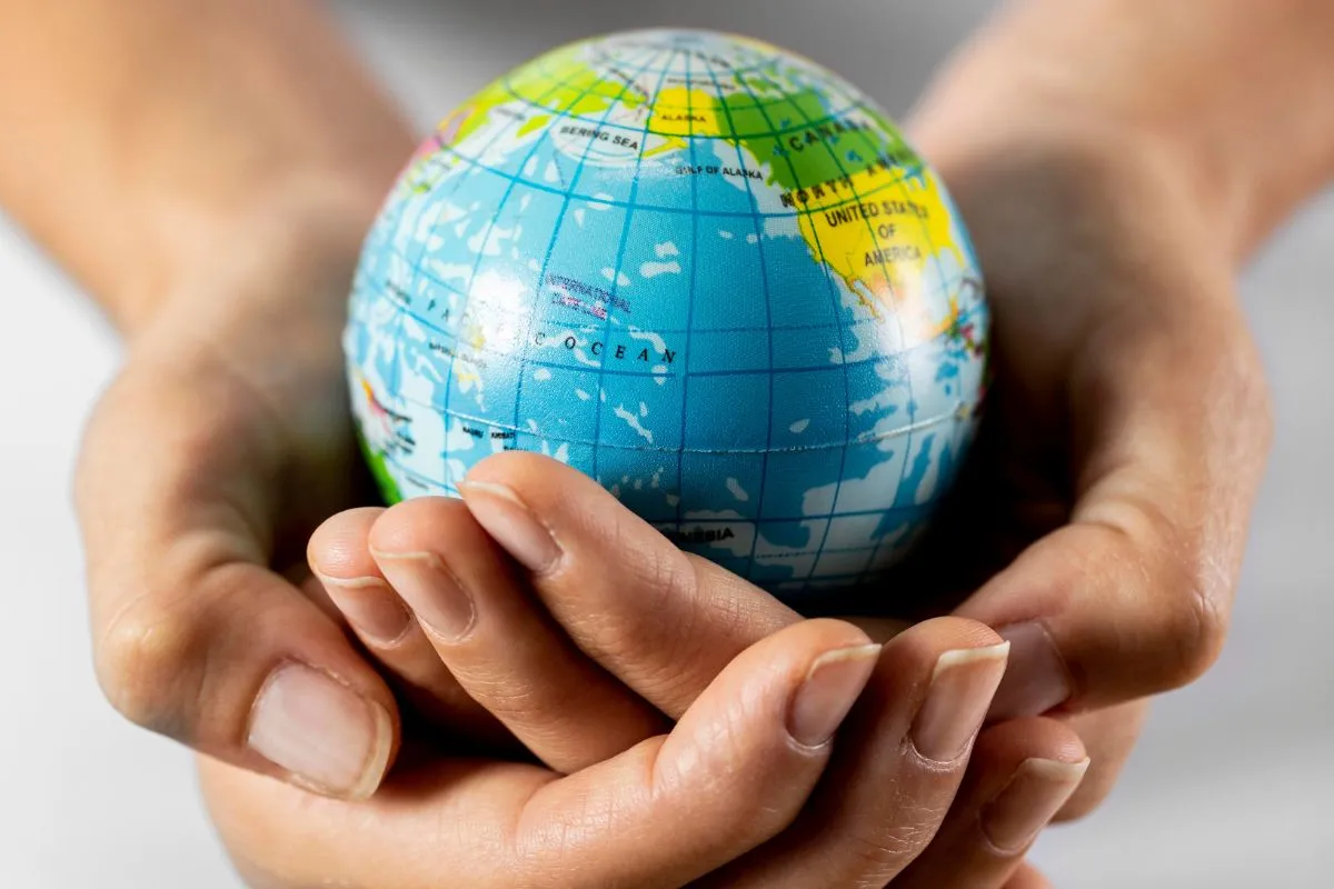 Mãos segurando pequeno globo terrestre representando preservação ambiental e responsabilidade global