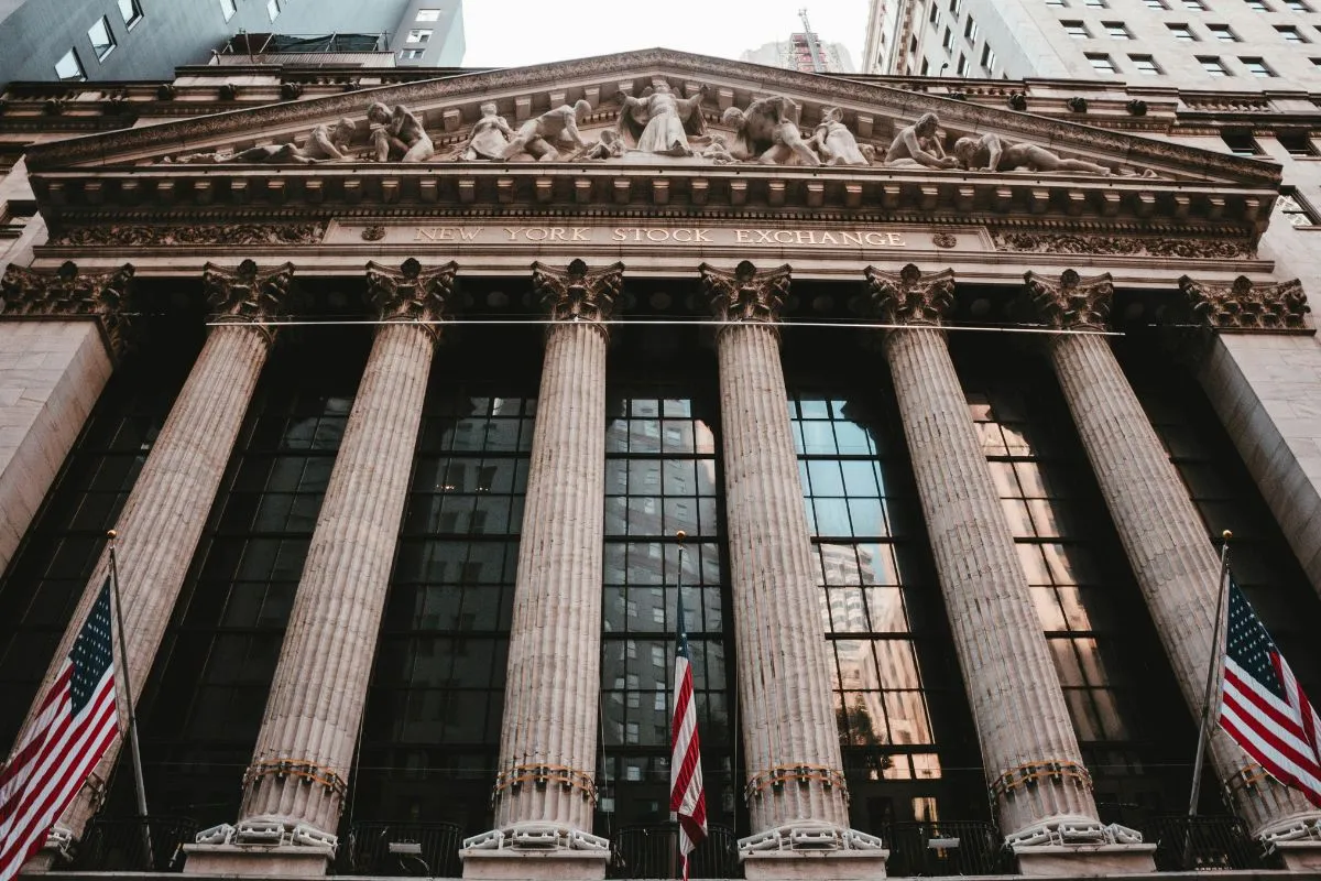 Fachada da Bolsa de Valores de Nova York com colunas e bandeiras dos Estados Unidos