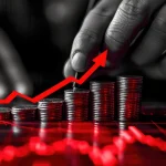 Pilhas de moedas com seta vermelha ascendente representando inflação e aumento de preços