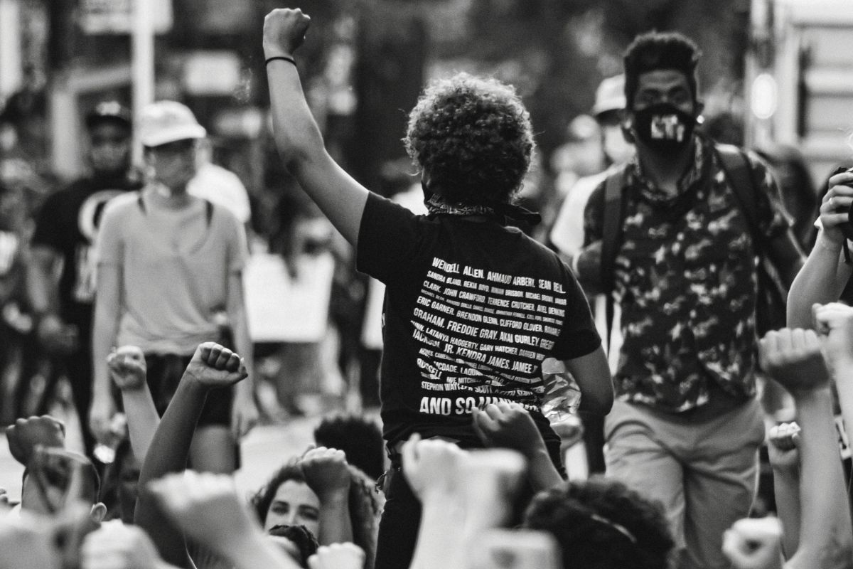 Pessoa com punho levantado em protesto por igualdade racial durante manifestação urbana