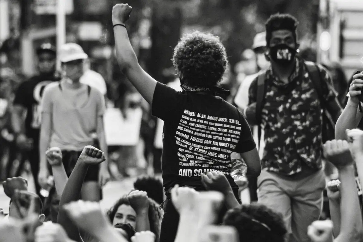 Pessoa com punho levantado em protesto por igualdade racial durante manifestação urbana