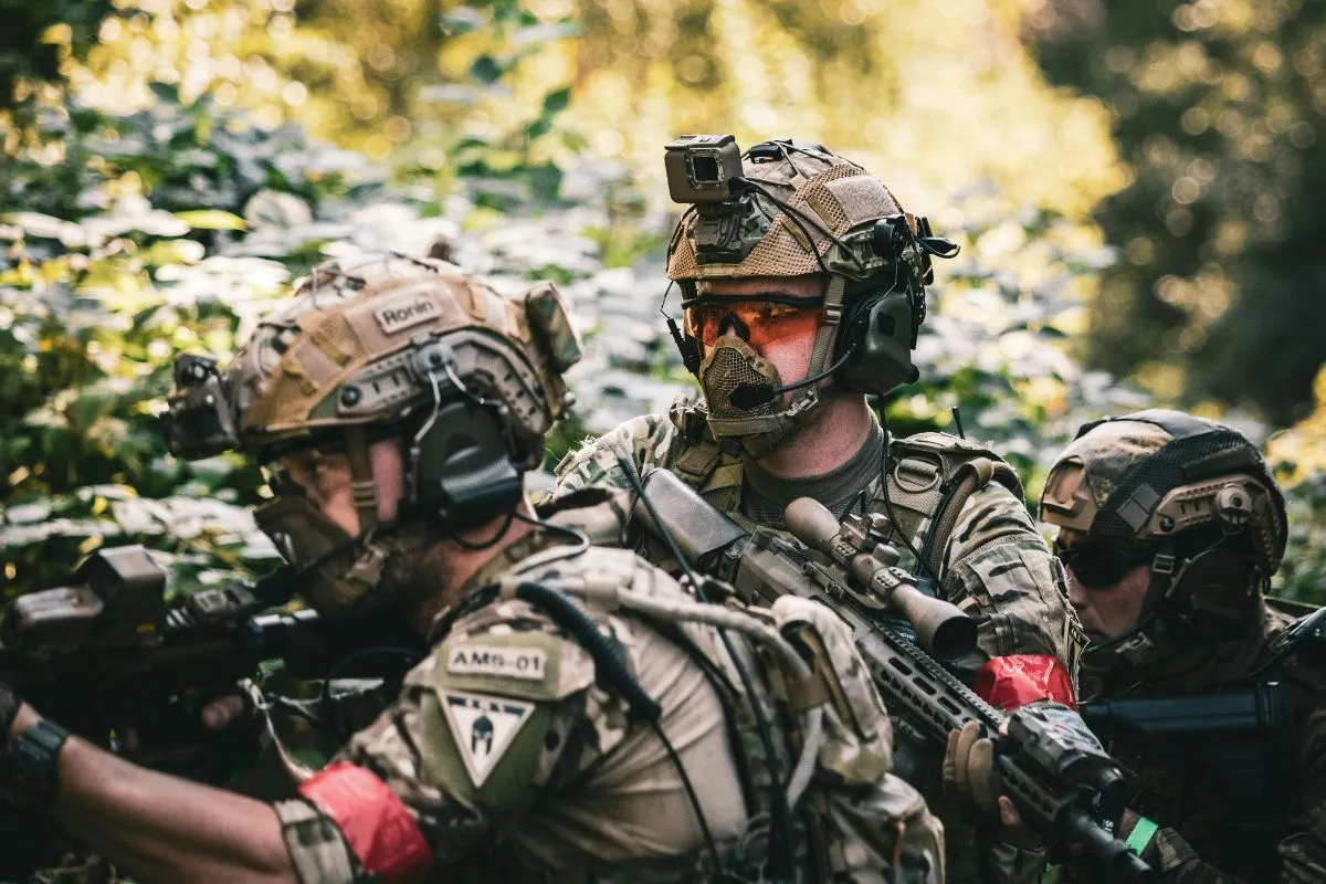 Soldados equipados em operação tática com armas em ambiente de floresta