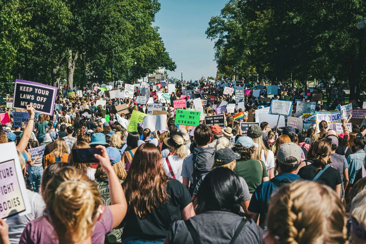 Multidão em manifestação com cartazes sobre direitos das mulheres e autonomia do corpo