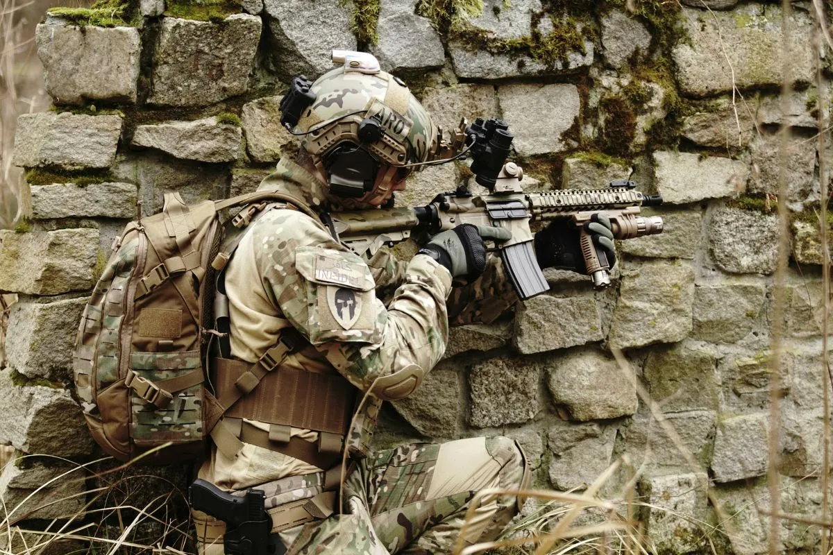 Soldado armado em posição tática próximo a parede durante operação militar