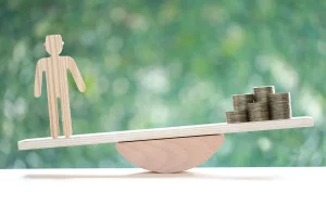 Balança com figura de pessoa de um lado e moedas do outro representando desigualdade econômica e poder de compra