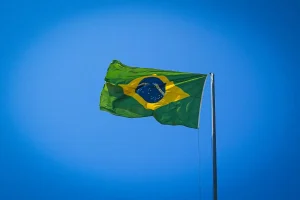 Bandeira do Brasil hasteada em mastro, tremulando ao vento sob céu azul limpo