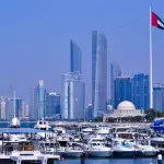 Bandeira dos Emirados Árabes Unidos com a cidade de Abu Dhabi ao fundo