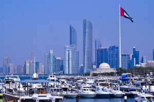 Bandeira dos Emirados Árabes Unidos com a cidade de Abu Dhabi ao fundo