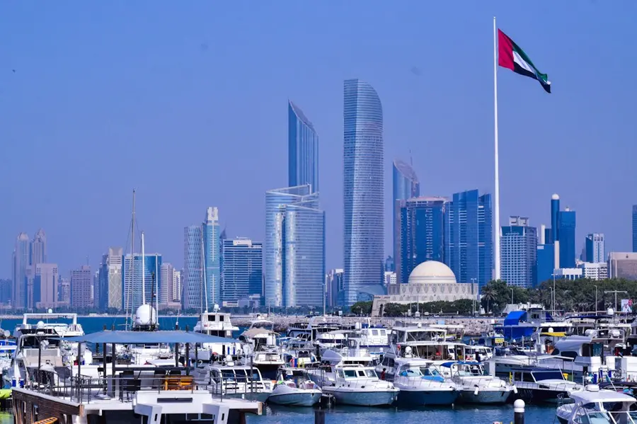 Bandeira dos Emirados Árabes Unidos com a cidade de Abu Dhabi ao fundo