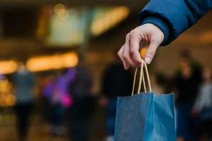 Pessoa segurando sacola de compras em ambiente urbano representando consumo e poder de compra
