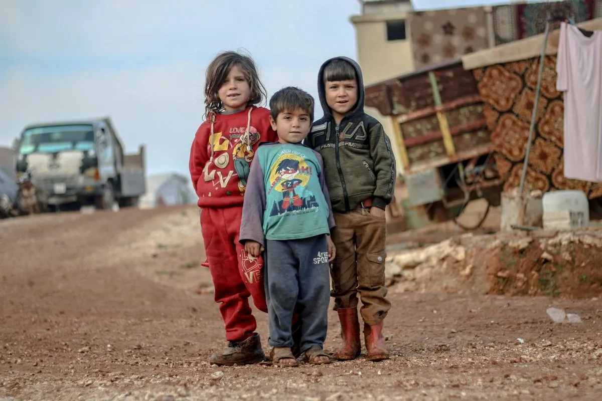 Crianças em área rural com condições precárias representando crise de refugiados