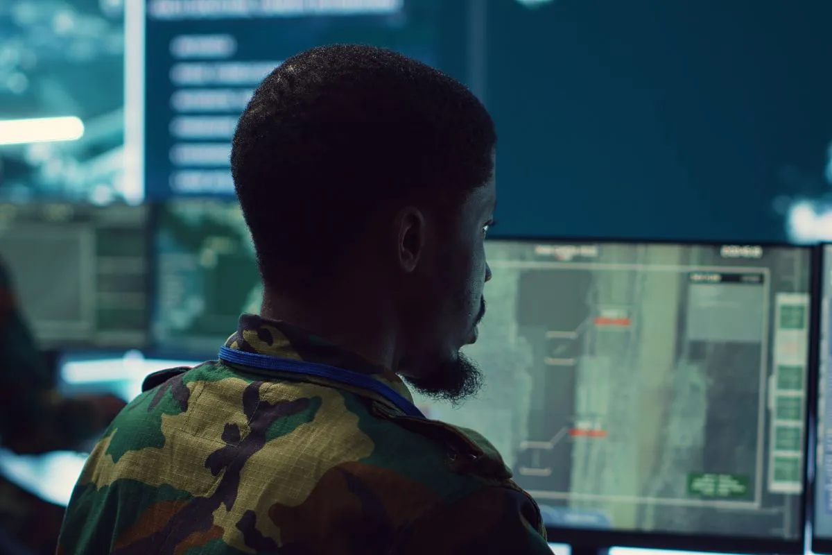 Militar analisando dados em tela de computador em centro de monitoramento estratégico