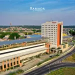 Vista aérea da fachada do Hotel Ramada by Wyndham Manaus Torres Center, destacando o edifício moderno e a localização estratégica próxima a vias de acesso