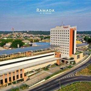 Vista aérea da fachada do Hotel Ramada by Wyndham Manaus Torres Center, destacando o edifício moderno e a localização estratégica próxima a vias de acesso