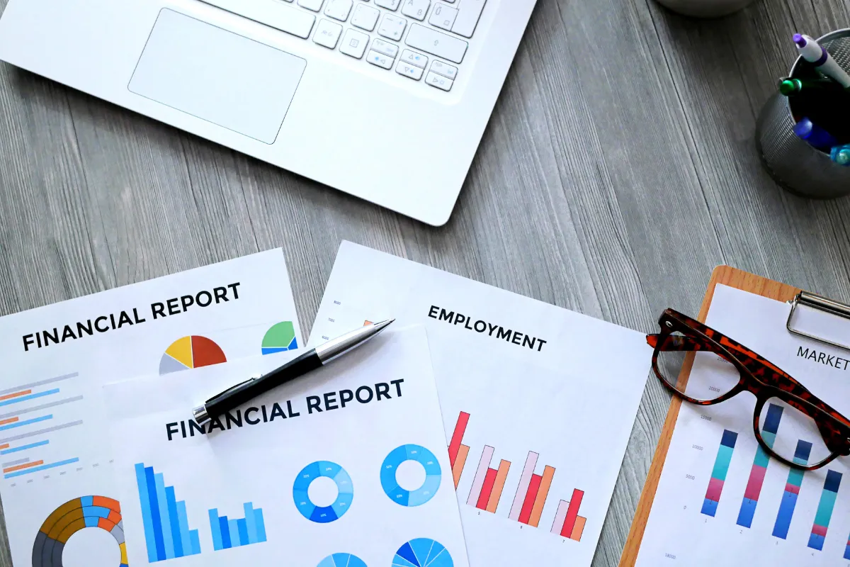 Relatórios financeiros e gráficos de emprego organizados sobre mesa durante análise do mercado de trabalho brasileiro