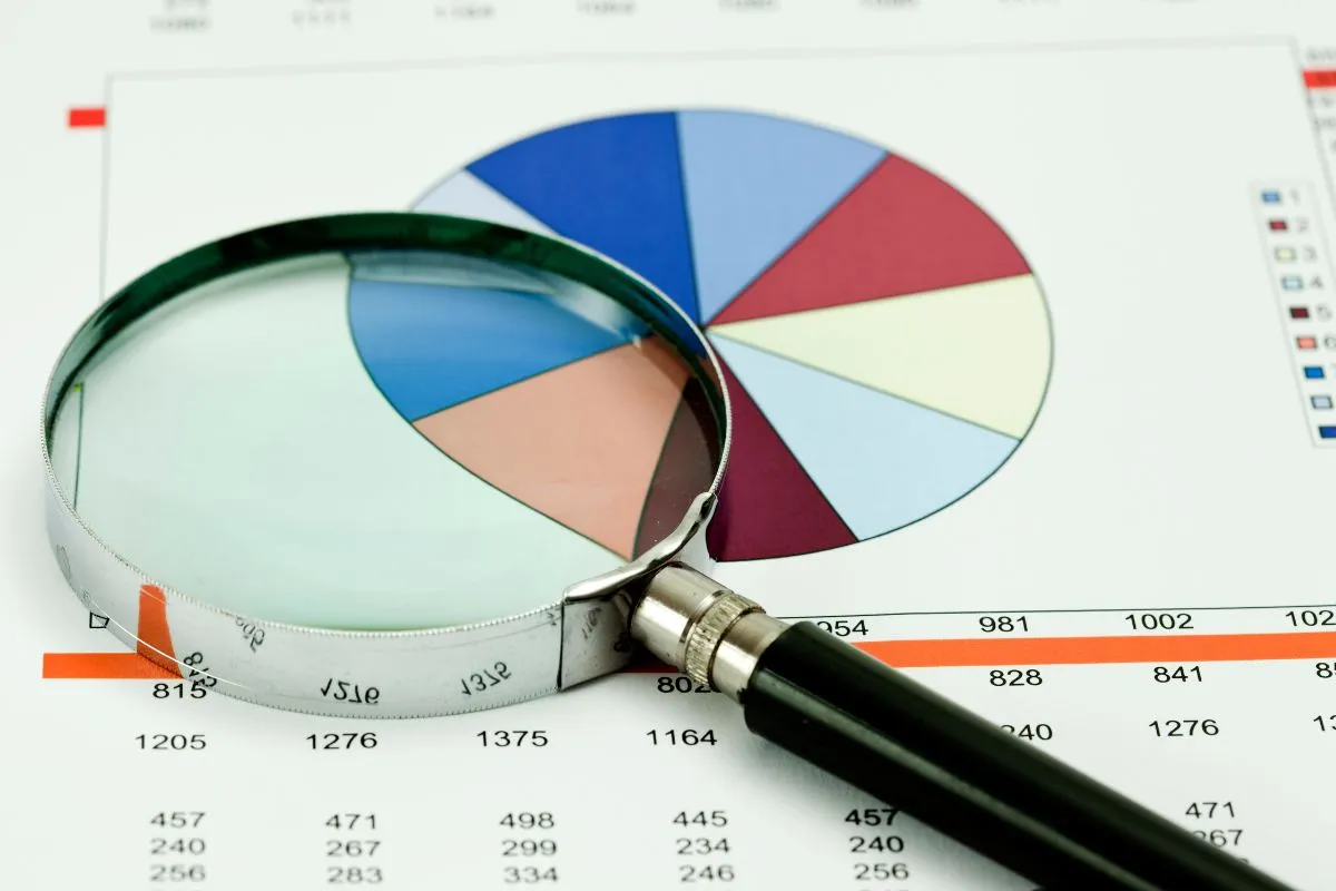 Lupa sobre gráfico financeiro colorido representando análise de indicadores do orçamento público brasileiro