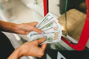 Pessoa contando notas de dólar americano em balcão de casa de câmbio