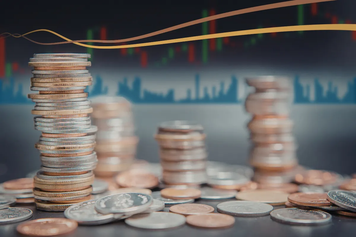 Pilha de moedas diante de gráficos financeiros desfocados representando crescimento financeiro e políticas econômicas