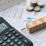 Calculadora e blocos com a palavra tax sobre documentos fiscais relacionados à declaração de impostos