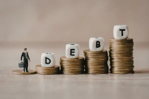 Moedas empilhadas formando a palavra debt representando dívida pública e endividamento econômico do Brasil