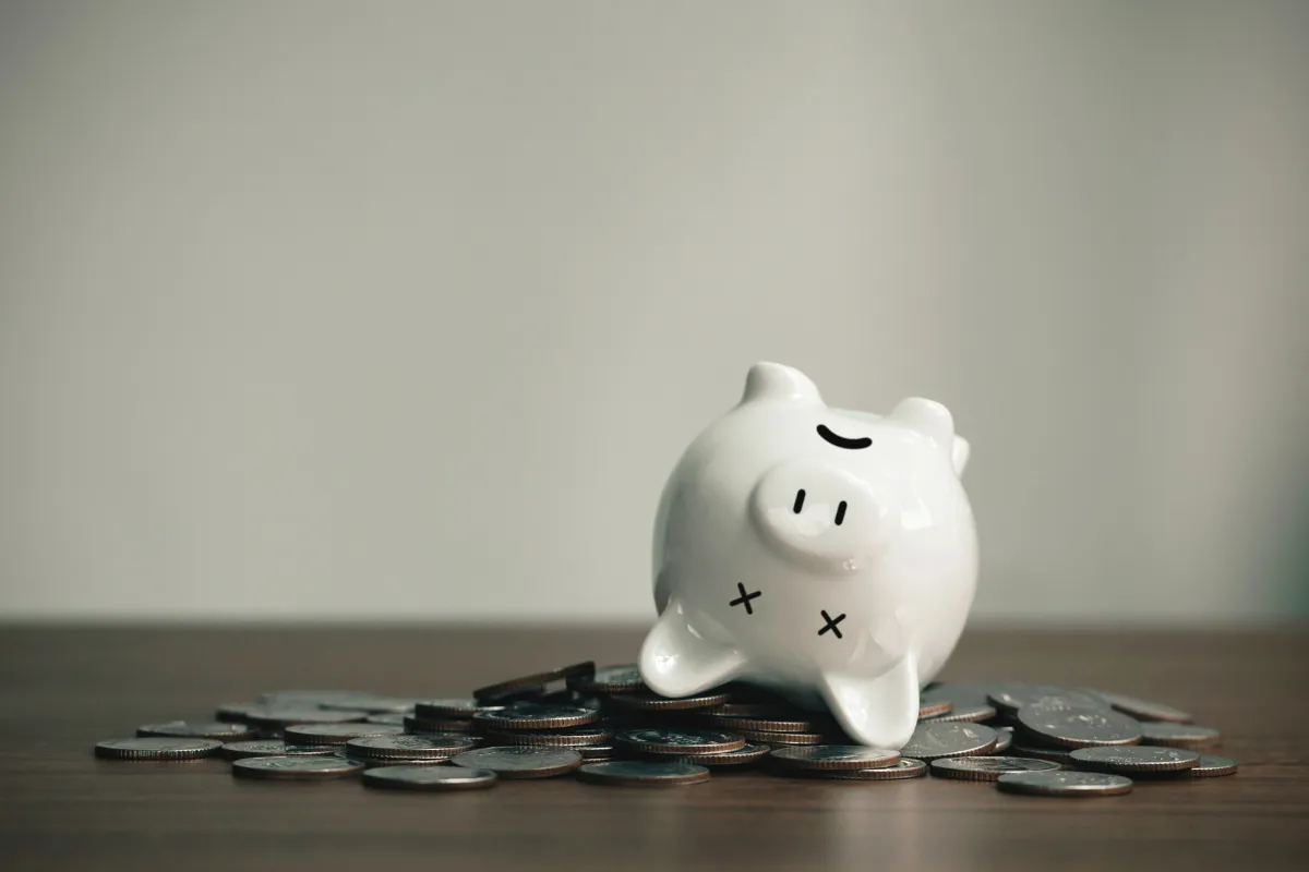 Cofrinho branco cercado por moedas representando economia popular e efeitos das isenções fiscais