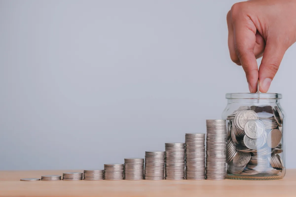 Moedas organizadas ao lado de pote de vidro representando economia doméstica e efeitos de subsídios financeiros